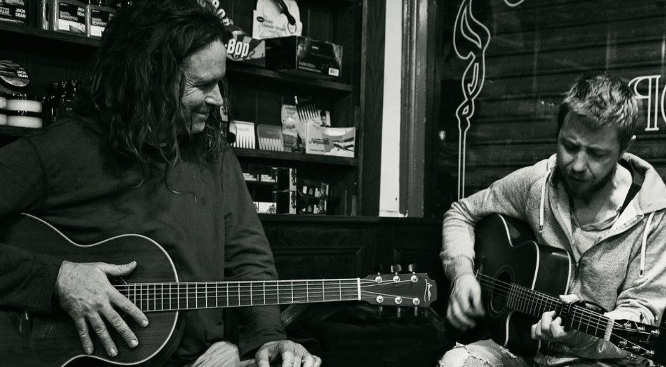 Two musicians playing acoustic guitars together